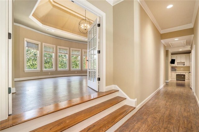 corridor with attic access, crown molding, baseboards, and wood finished floors