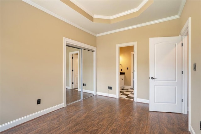 unfurnished bedroom with a tray ceiling, crown molding, baseboards, and dark wood-type flooring