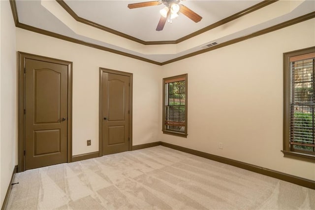 unfurnished bedroom featuring visible vents, a raised ceiling, carpet flooring, and ornamental molding