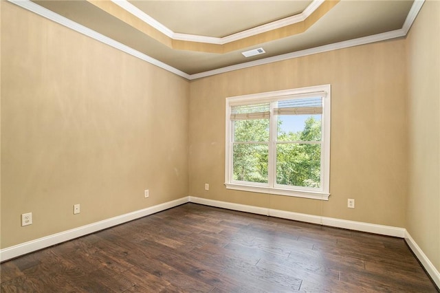 empty room featuring dark wood-style floors, a tray ceiling, visible vents, and crown molding