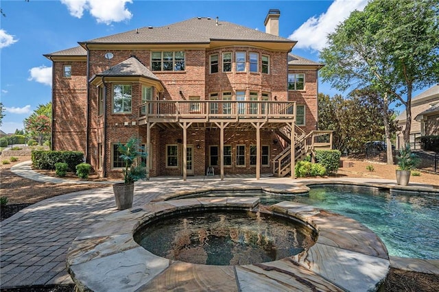 back of house featuring brick siding, a patio, a chimney, and a wooden deck