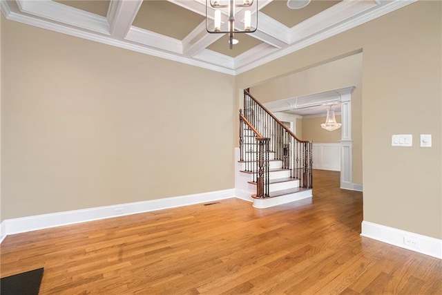 interior space featuring coffered ceiling, stairs, light wood finished floors, an inviting chandelier, and crown molding