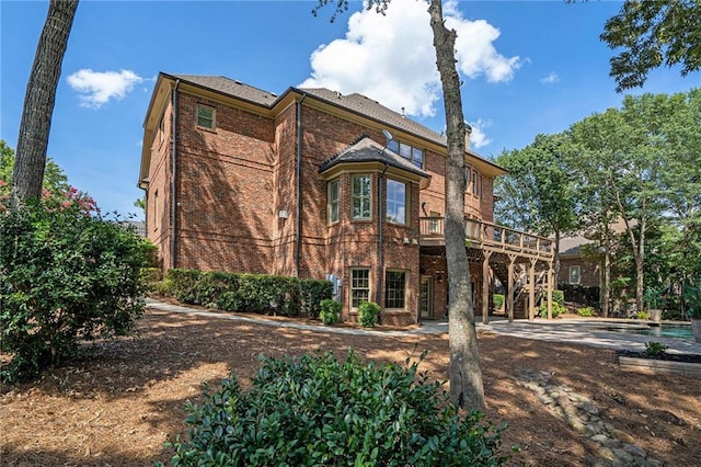 view of front of home with a wooden deck, stairway, and brick siding