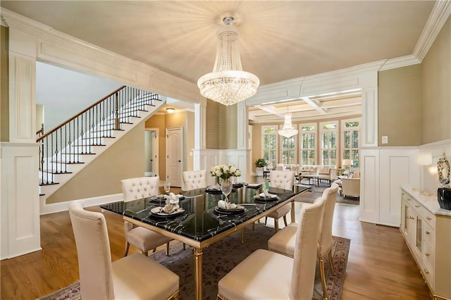 dining area featuring wood finished floors, coffered ceiling, a decorative wall, and stairs