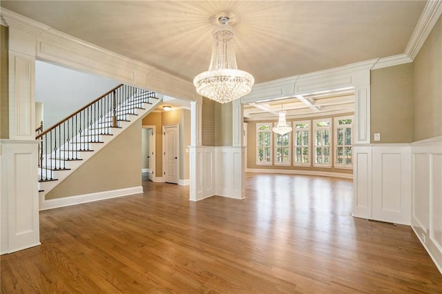 interior space with crown molding, stairs, a decorative wall, and wood finished floors