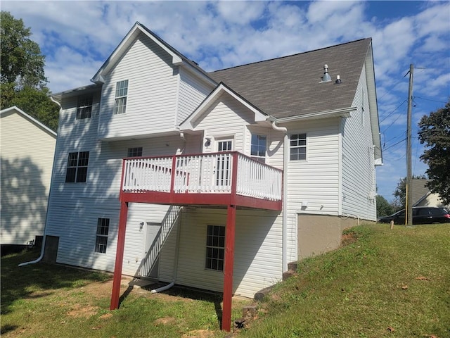 rear view of property featuring a lawn and a deck