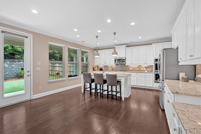 12 Pine St, Roswell, GA 30075 - kitchen with appliances with stainless steel finishes, a kitchen bar, decorative backsplash, white cabinets, and an island with sink