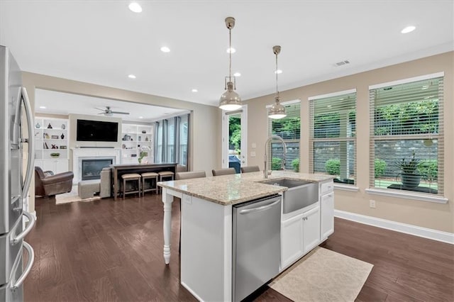12 Pine St, Roswell, GA 30075 - kitchen with appliances with stainless steel finishes, a sink, white cabinets, light stone counters, and a center island with sink