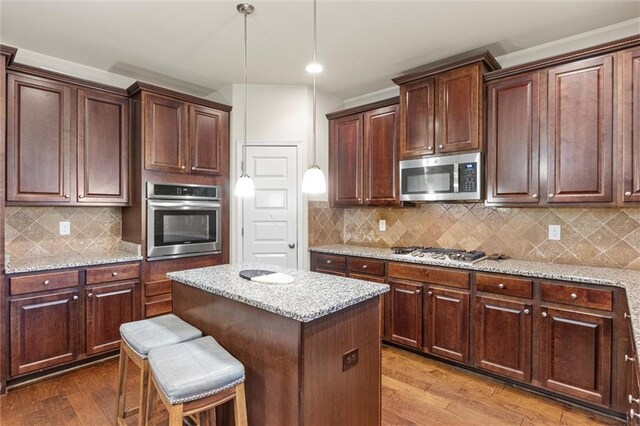 kitchen with light stone counters, tasteful backsplash, stainless steel appliances, and light hardwood / wood-style flooring