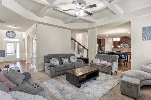 living room featuring beam ceiling, ceiling fan, coffered ceiling, light hardwood / wood-style floors, and ornamental molding