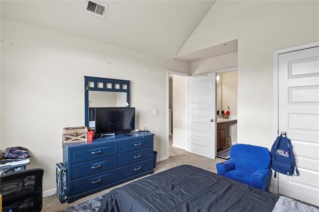 bedroom featuring light carpet, ensuite bathroom, and vaulted ceiling