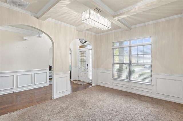 spare room featuring beam ceiling, dark hardwood / wood-style floors, an inviting chandelier, and ornamental molding