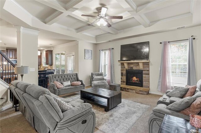 carpeted living room featuring a stone fireplace, a wealth of natural light, ceiling fan, and ornamental molding