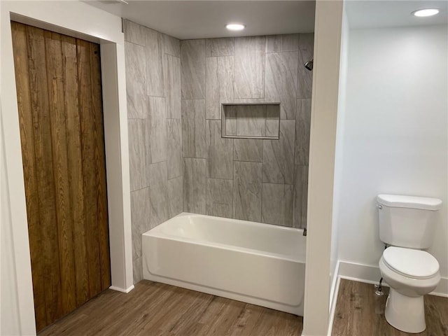 bathroom with hardwood / wood-style floors, tiled shower / bath combo, and toilet