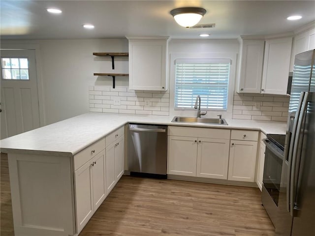 kitchen featuring kitchen peninsula, sink, white cabinets, and stainless steel appliances