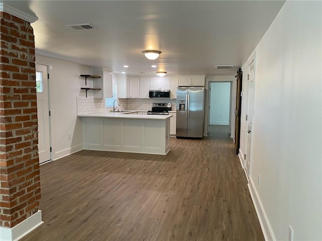 kitchen with kitchen peninsula, appliances with stainless steel finishes, dark hardwood / wood-style flooring, decorative backsplash, and white cabinets