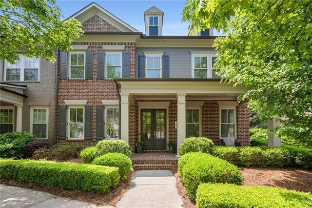 view of front of home featuring french doors, a porch, and brick siding