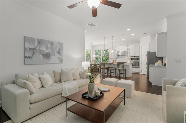 living area featuring visible vents, crown molding, wood finished floors, recessed lighting, and a ceiling fan