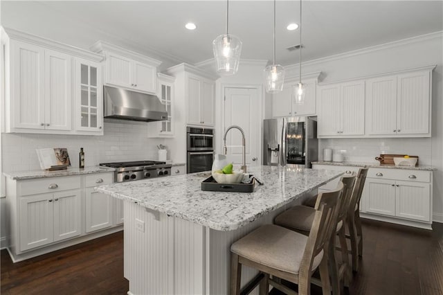kitchen with under cabinet range hood, stainless steel appliances, white cabinetry, and tasteful backsplash