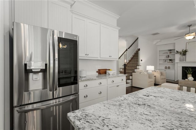kitchen with white cabinets, stainless steel fridge, a ceiling fan, open floor plan, and ornamental molding