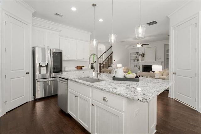 kitchen with ceiling fan, appliances with stainless steel finishes, a sink, a fireplace, and visible vents