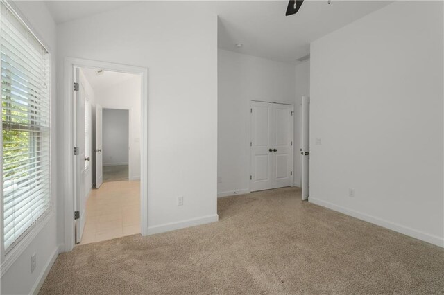 unfurnished bedroom with baseboards, vaulted ceiling, and light carpet