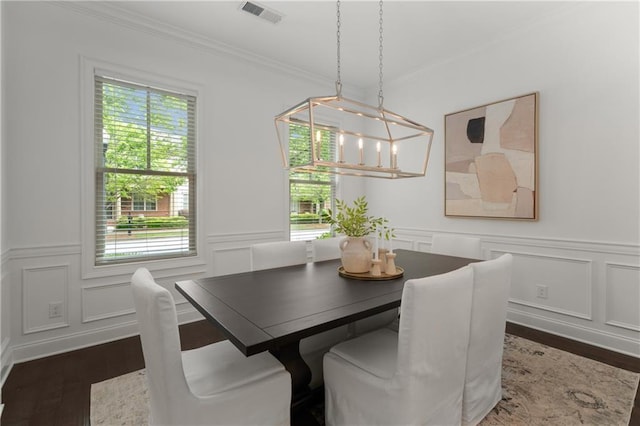 dining area featuring visible vents, crown molding, a decorative wall, and a healthy amount of sunlight