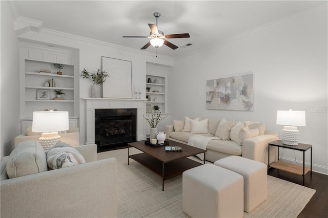 living room featuring crown molding, a ceiling fan, wood finished floors, and built in shelves