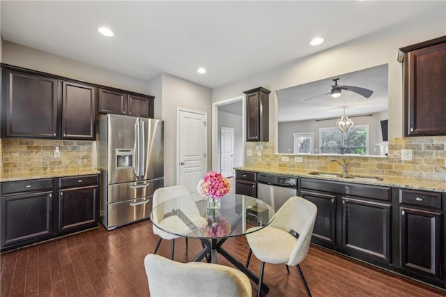 kitchen featuring a sink, dark brown cabinetry, backsplash, appliances with stainless steel finishes, and light stone counters
