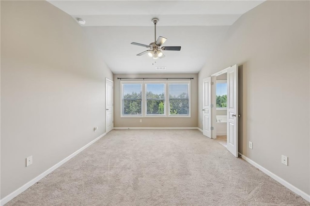 unfurnished room with visible vents, vaulted ceiling, light carpet, a ceiling fan, and baseboards