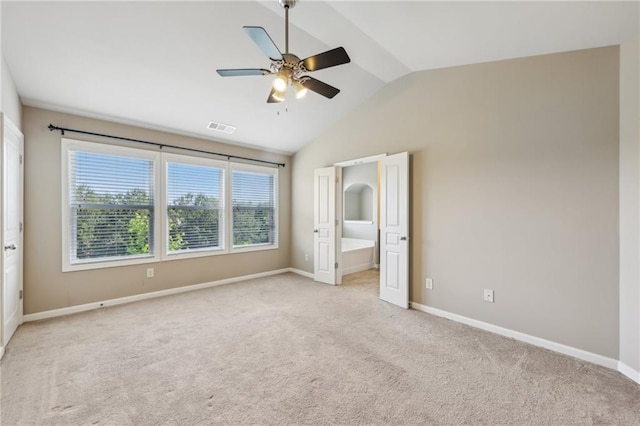 unfurnished bedroom featuring light colored carpet, lofted ceiling, visible vents, and multiple windows