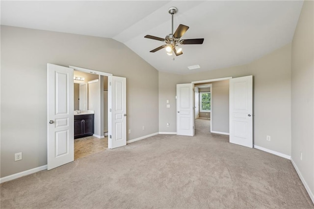 unfurnished bedroom with light colored carpet, ensuite bath, vaulted ceiling, and baseboards
