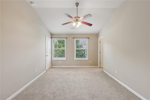 carpeted spare room with lofted ceiling, baseboards, a ceiling fan, and visible vents