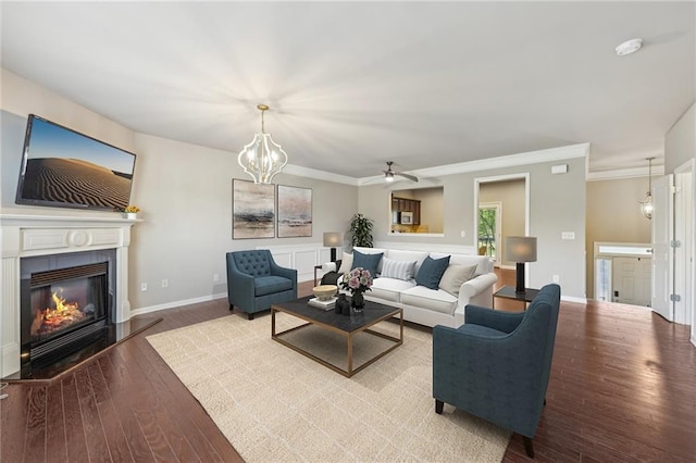 living area featuring wood finished floors, crown molding, a ceiling fan, baseboards, and a glass covered fireplace