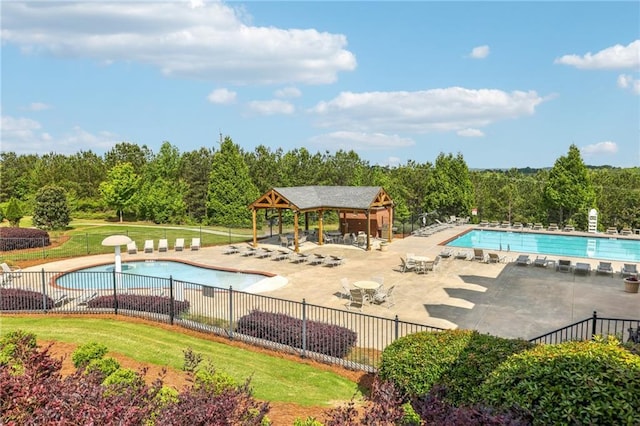 community pool with a patio area, fence, and a gazebo