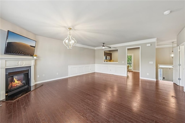 unfurnished living room featuring ornamental molding, a glass covered fireplace, ceiling fan with notable chandelier, and wood finished floors