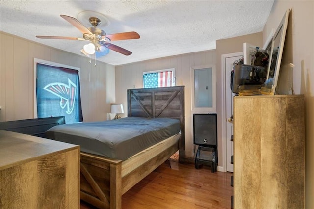 bedroom with ceiling fan, a textured ceiling, and hardwood / wood-style flooring