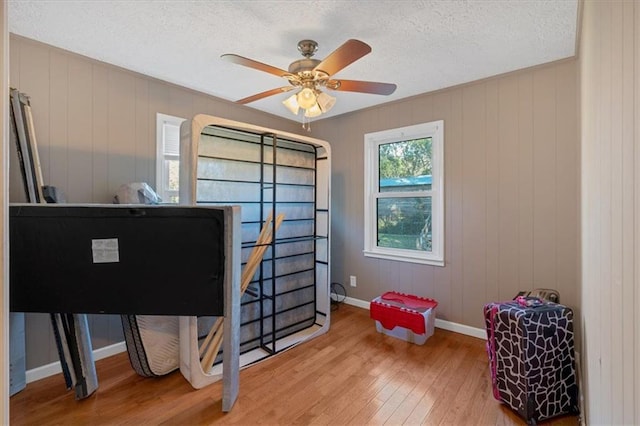 office area featuring a textured ceiling, ceiling fan, wood-type flooring, and wood walls