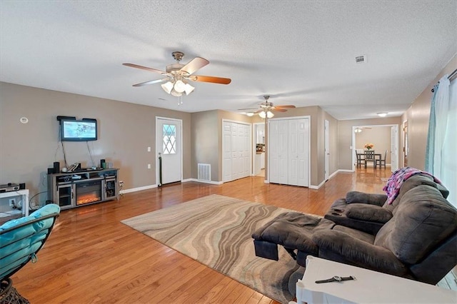 living room with ceiling fan, wood-type flooring, and a textured ceiling