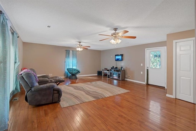 living room with ceiling fan, hardwood / wood-style floors, and a textured ceiling