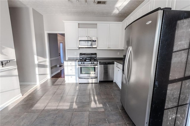 335 Wilma Ct SW, Atlanta, GA 30331 - kitchen with stainless steel appliances, white cabinets, a textured ceiling, dark countertops, and dark tile patterned floors