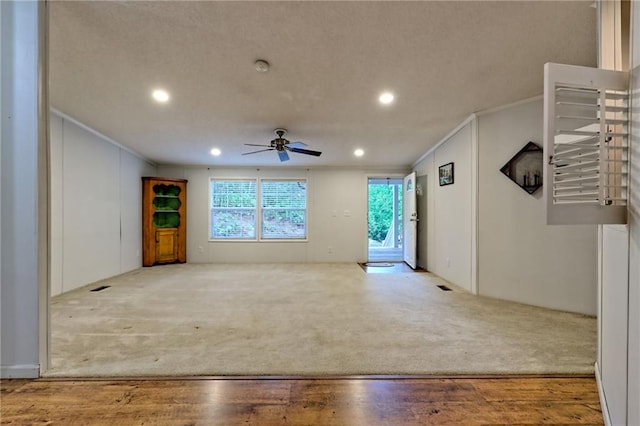 unfurnished living room featuring crown molding, a ceiling fan, carpet flooring, recessed lighting, and wood finished floors