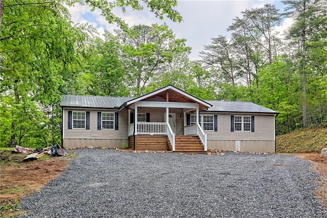 manufactured / mobile home with a porch, driveway, and metal roof