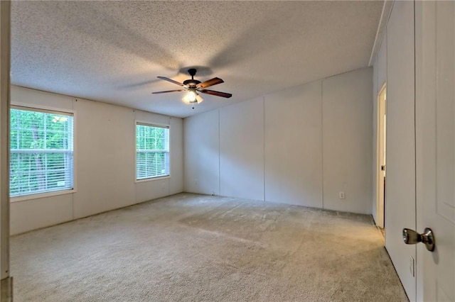 carpeted spare room with ceiling fan and a textured ceiling