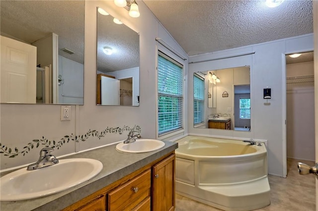 full bath featuring a textured ceiling, plenty of natural light, a garden tub, double vanity, and a shower