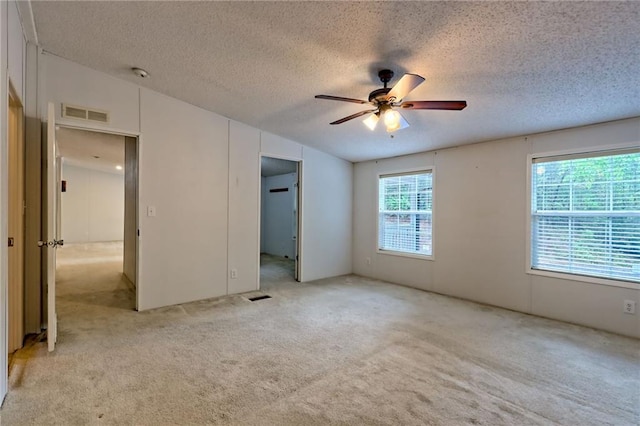 unfurnished bedroom featuring a textured ceiling, light carpet, and ceiling fan
