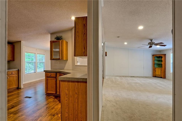 kitchen featuring a textured ceiling, brown cabinetry, ceiling fan, open floor plan, and recessed lighting