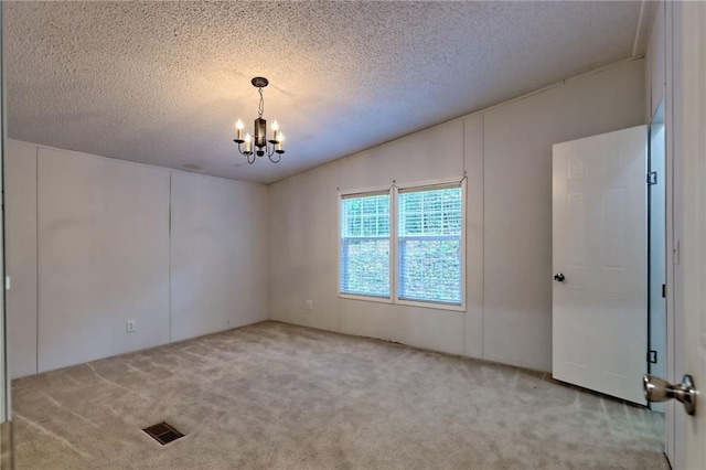 carpeted empty room featuring a chandelier and a textured ceiling