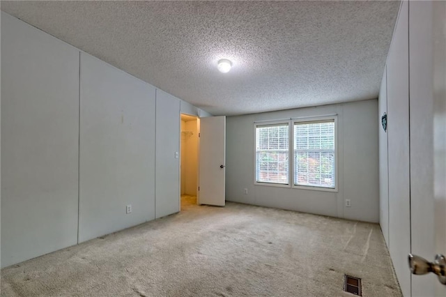 carpeted empty room featuring a textured ceiling