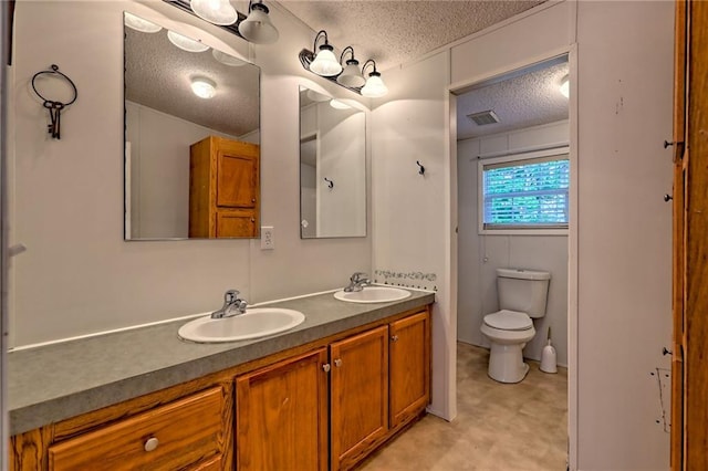 full bathroom with a textured ceiling, toilet, and double vanity